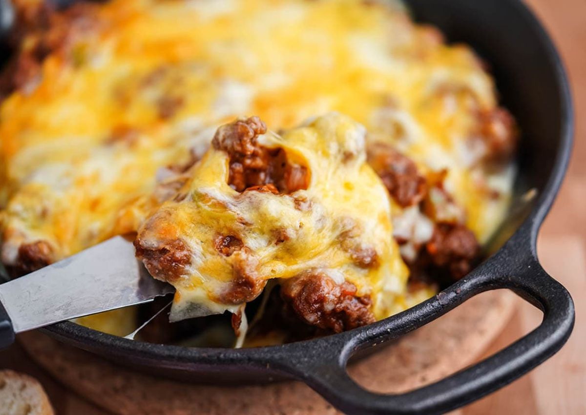 A close-up of a skillet containing melted cheese and browned ground meat.