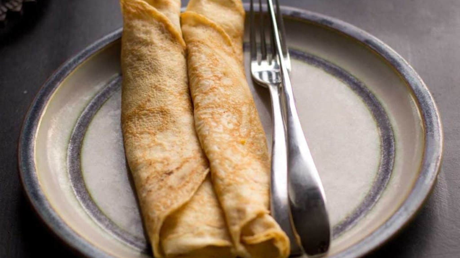 Two high protein sourdough crepes on a plate with a fork. 