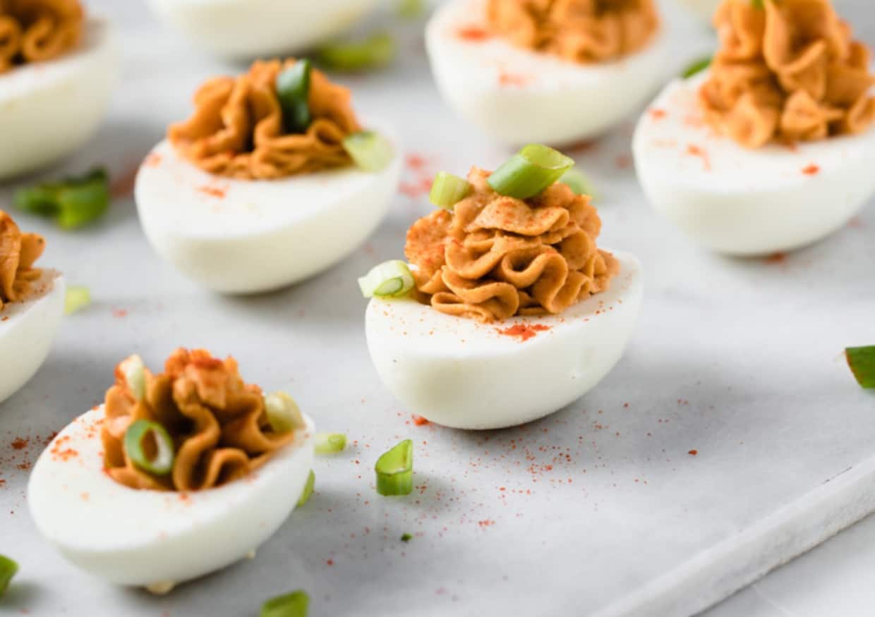Egg whipes filled with buffalo dip on a white background.