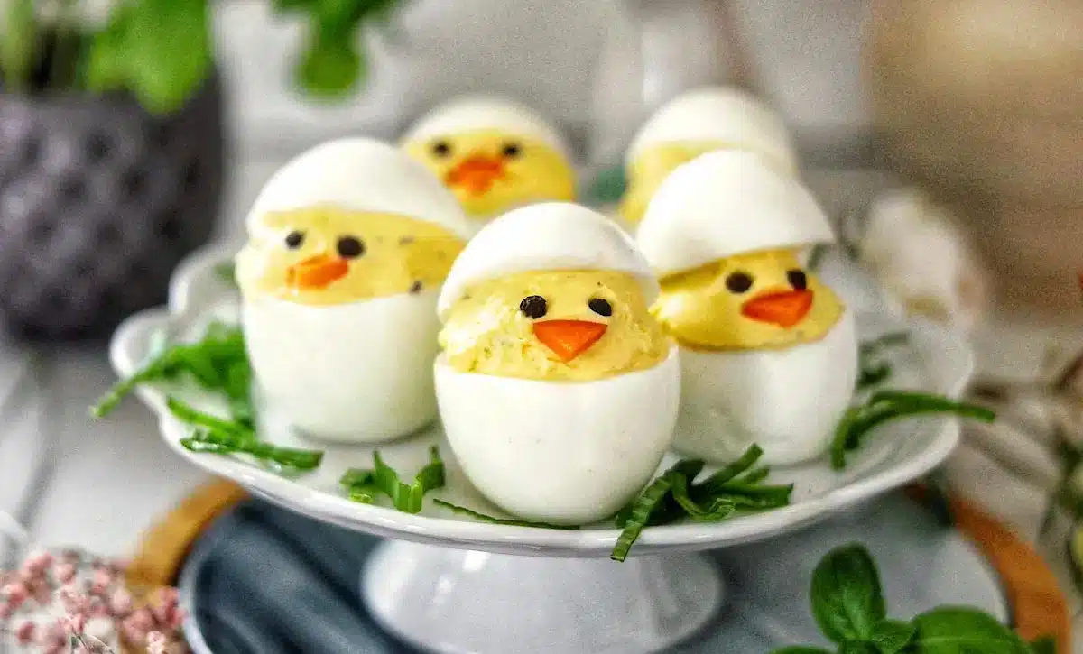 Deviled eggs decorated to look like chicks on a small plate.