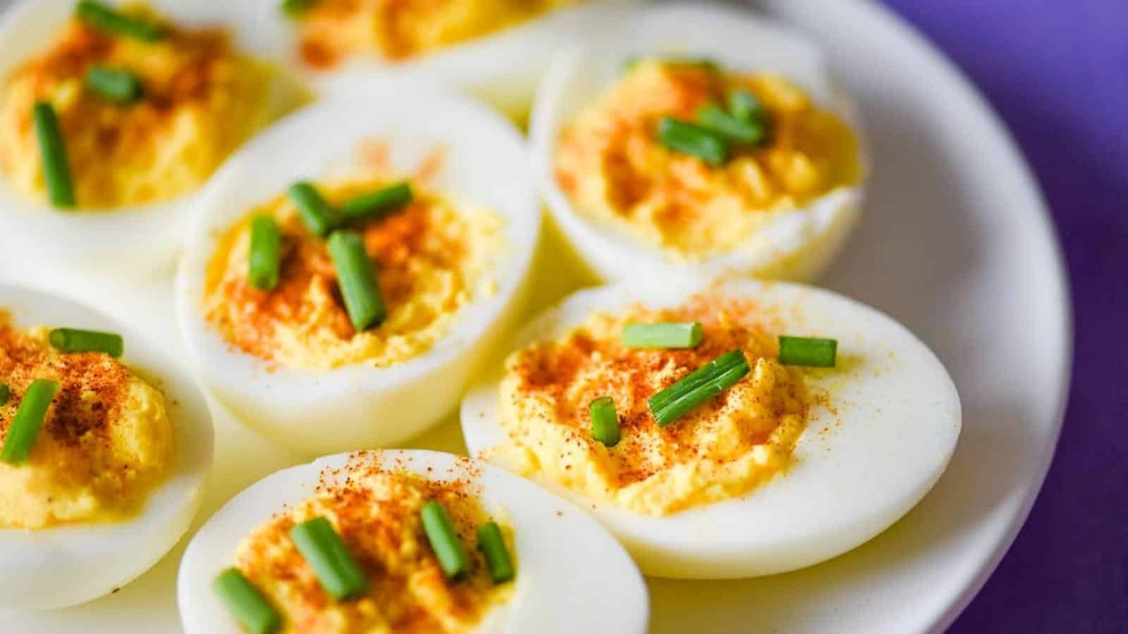 Deviled eggs on white plate topped with chives.