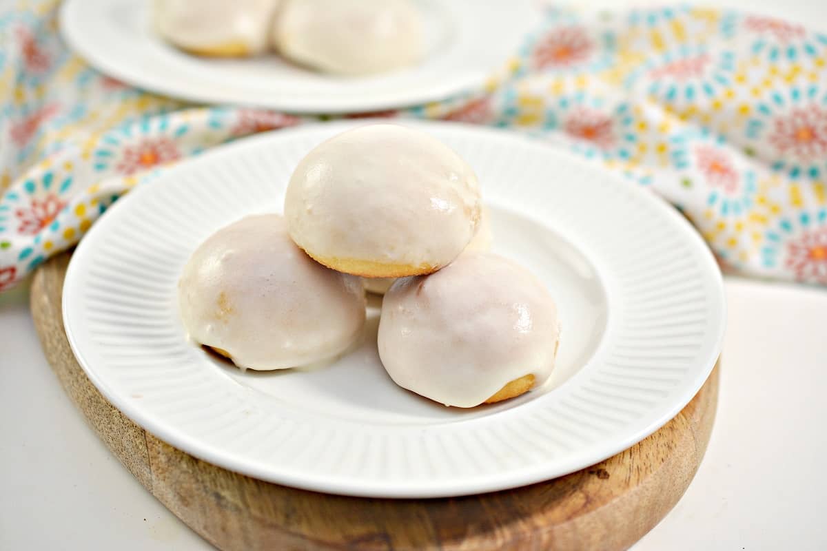Four keto donut holes on a white plate topped with icing.