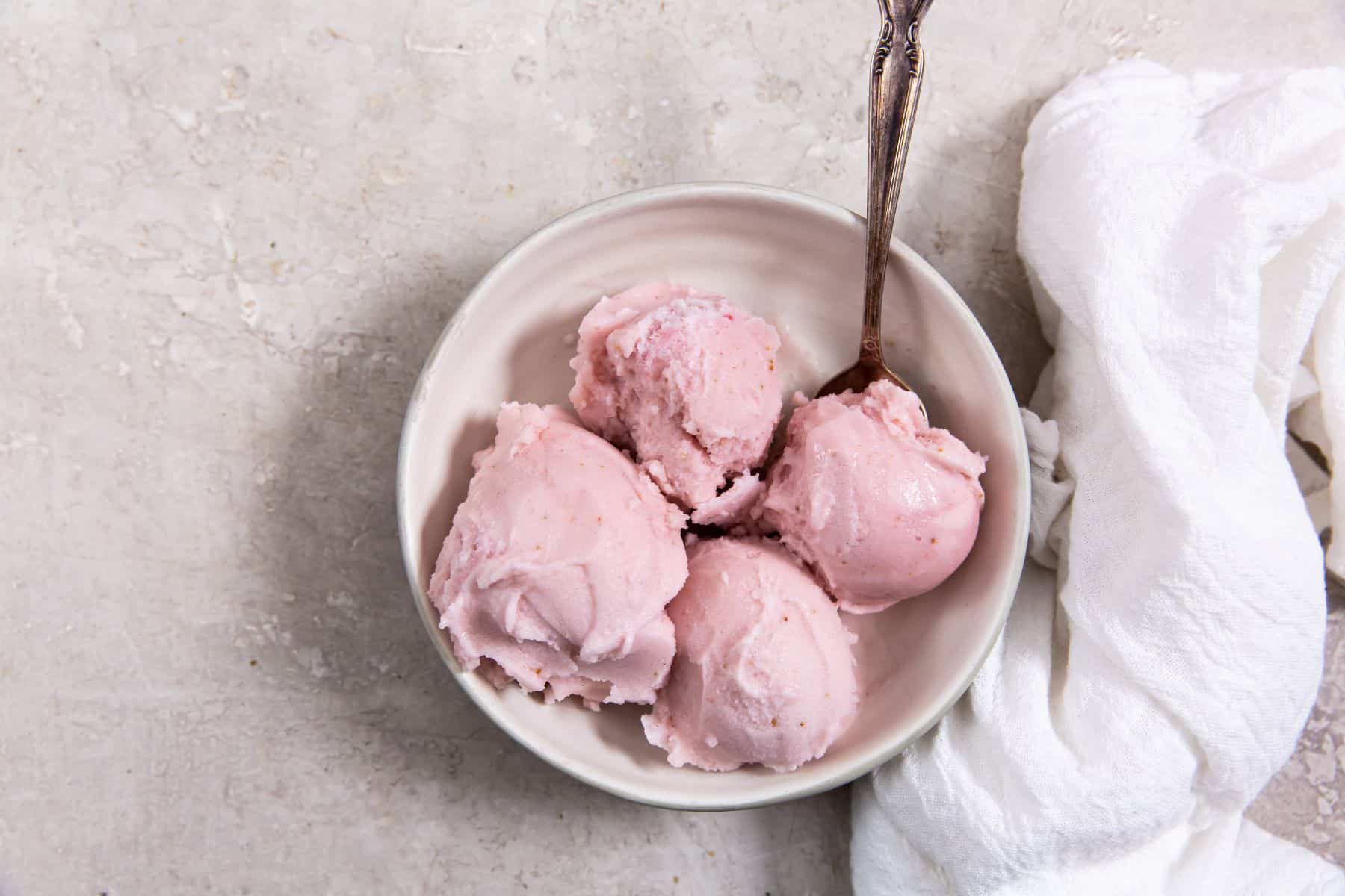 Strawberry ice cream in a small white bowl.
