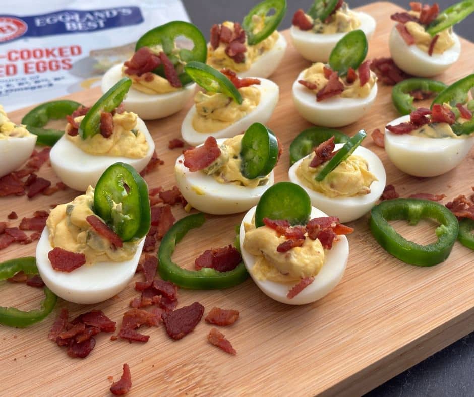 Jalapeno popper deviled eggs on a wooden cutting board.