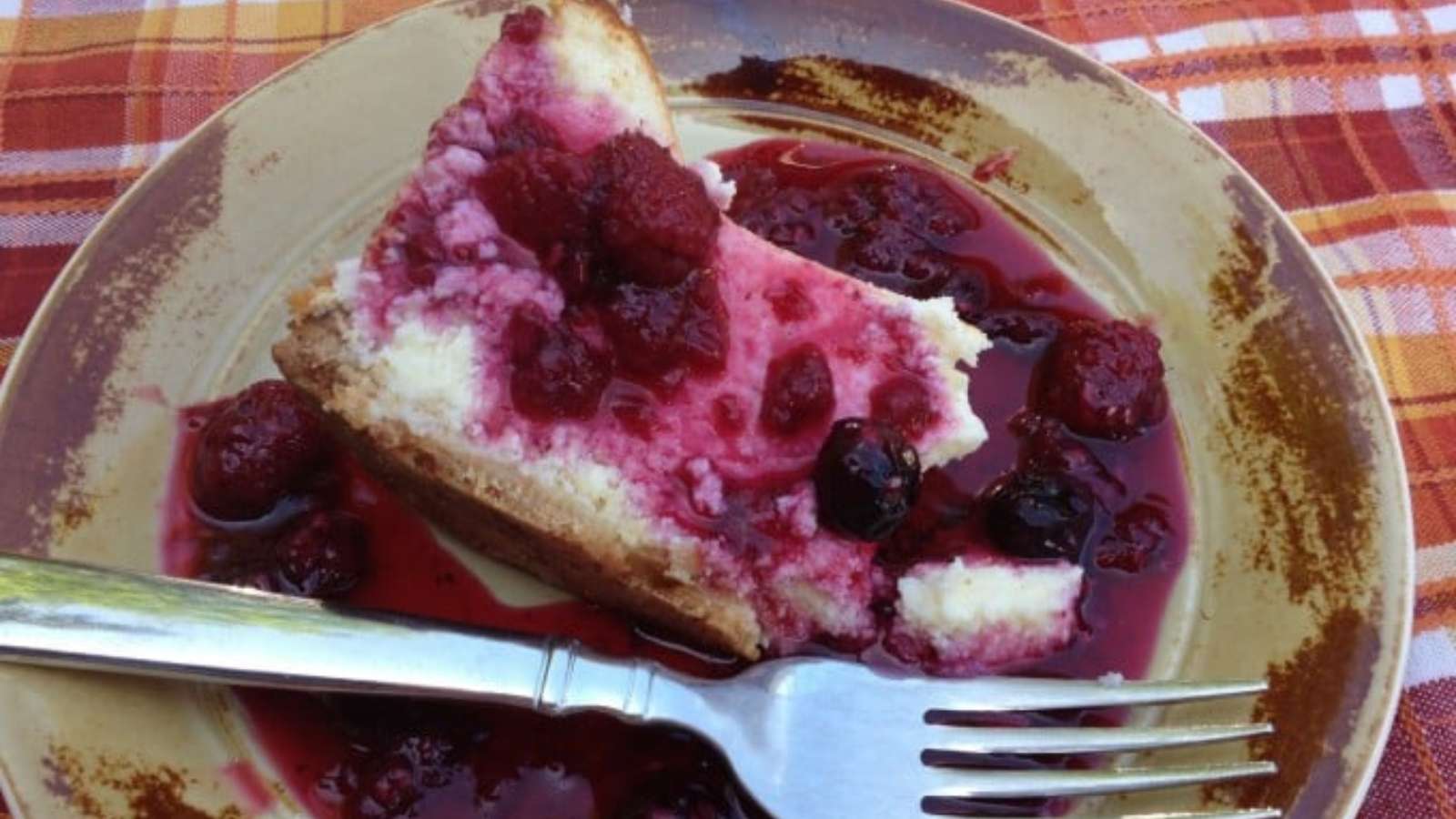Slice of cheesecake on a plate topped with raspberry sauce.