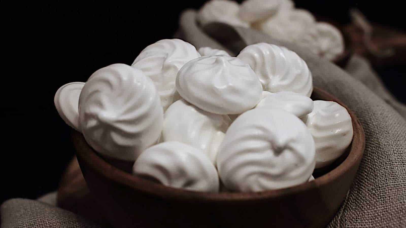 White meringue cookies in a wooden bowl.