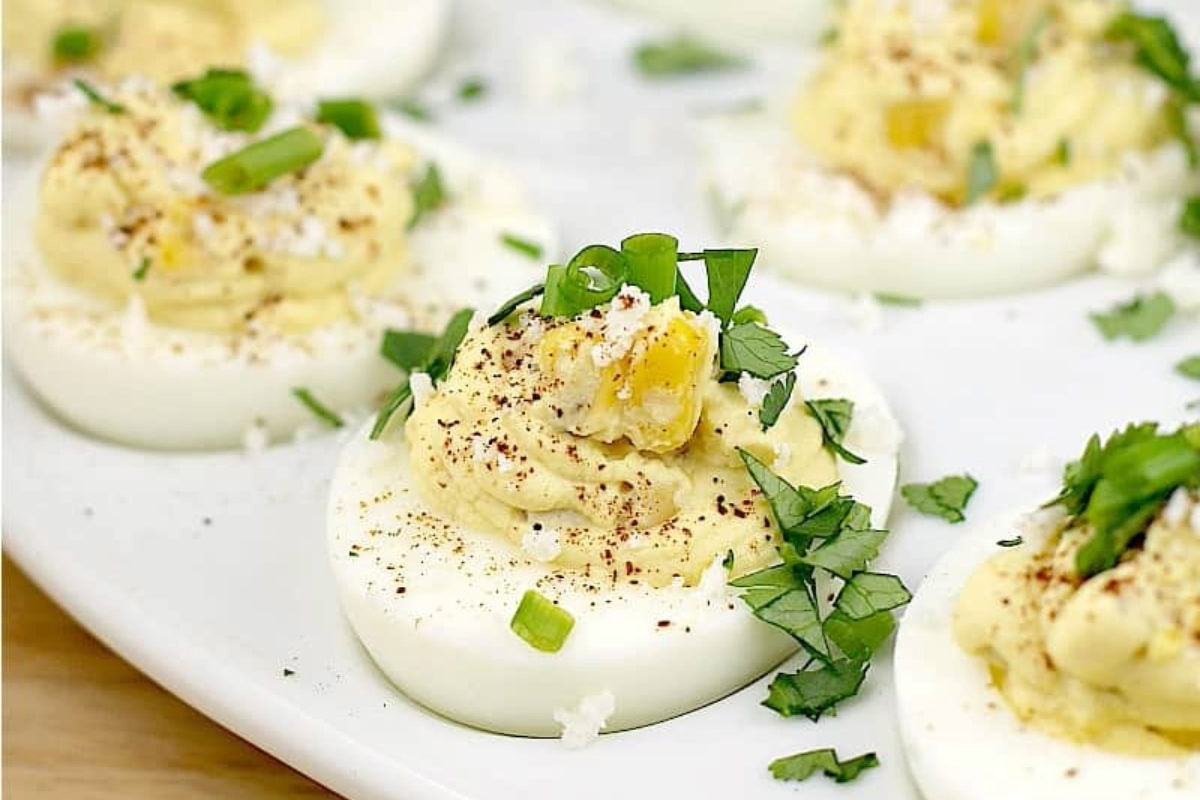 Mexican street corn deviled eggs on a white serving dish. 