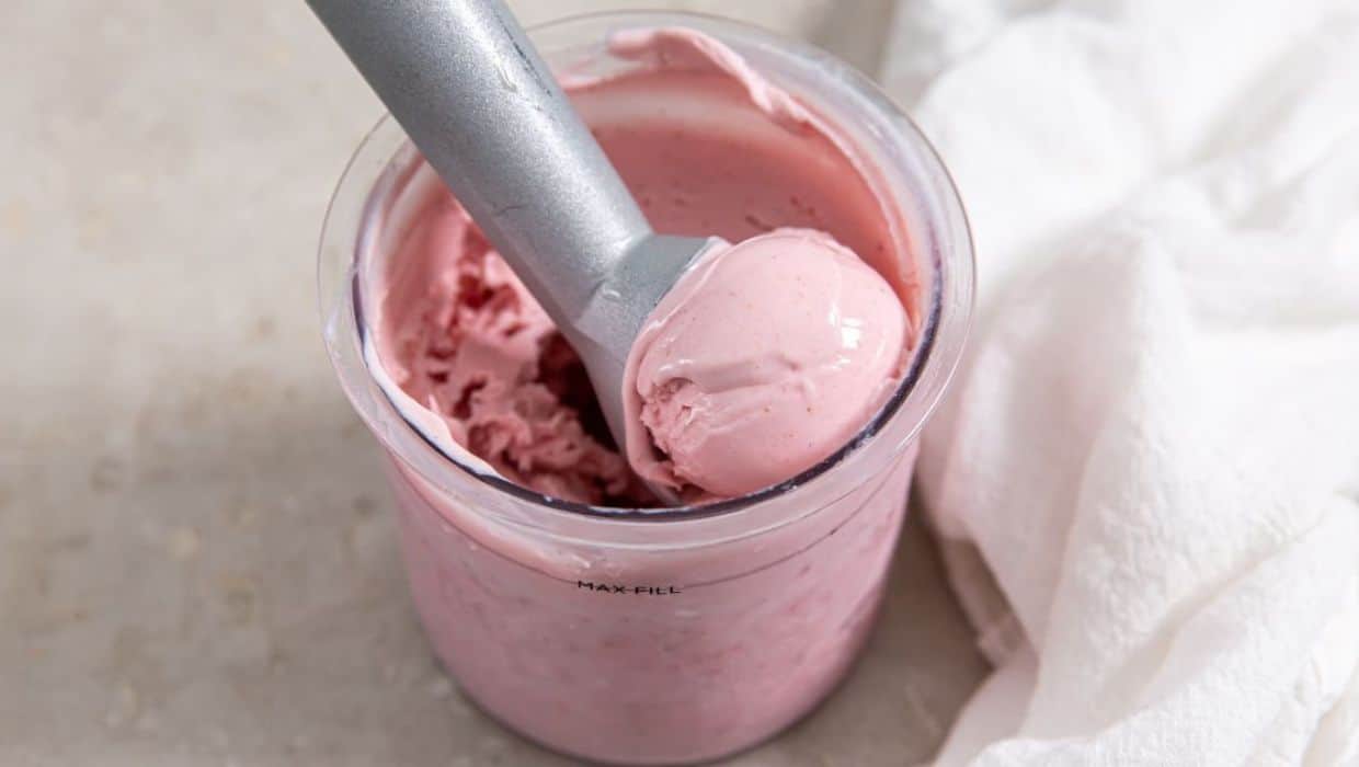 Strawberry ice cream being scooped out of a Ninja Creami bowl.