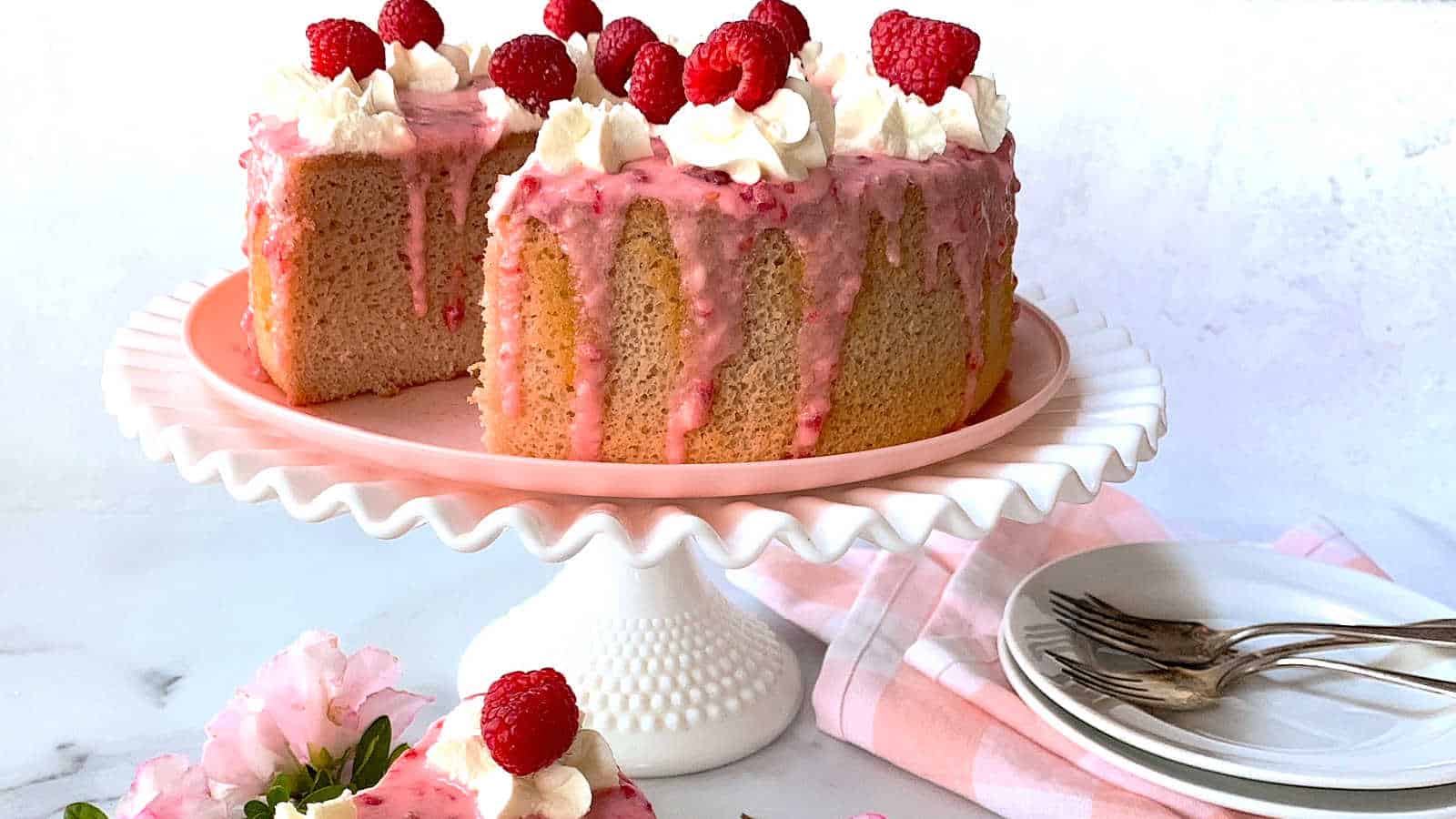 Raspberry cake on a white cake stand.