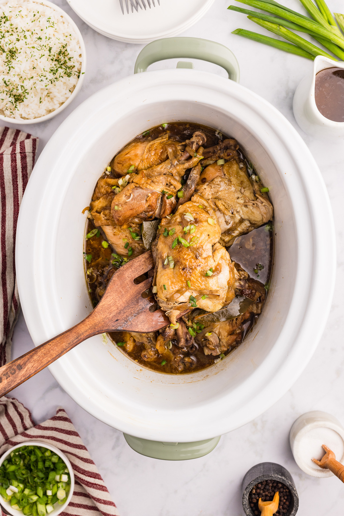 Chicken adobo in a white crockpot.