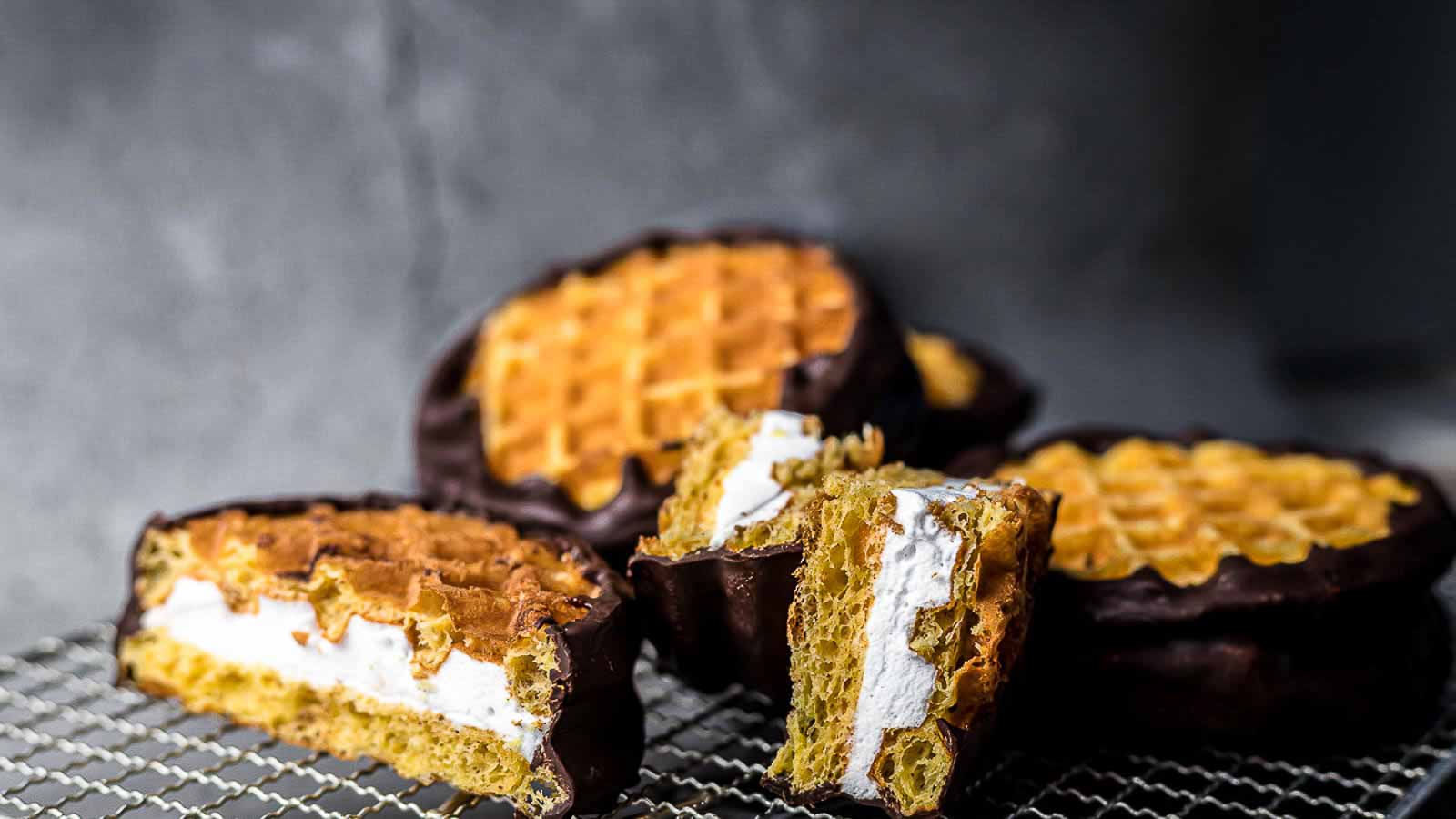Smokes chaffles dipped in a chocolate on a wire cooling rack.