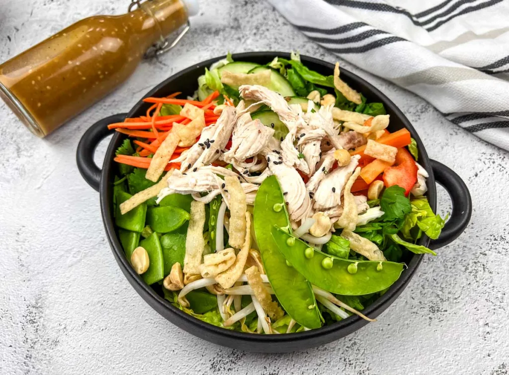 Black bowl full of asian chicken salad.