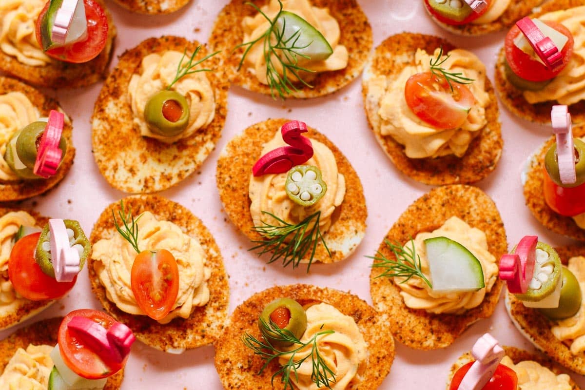 Bloody mary deviled eggs on a pink background.