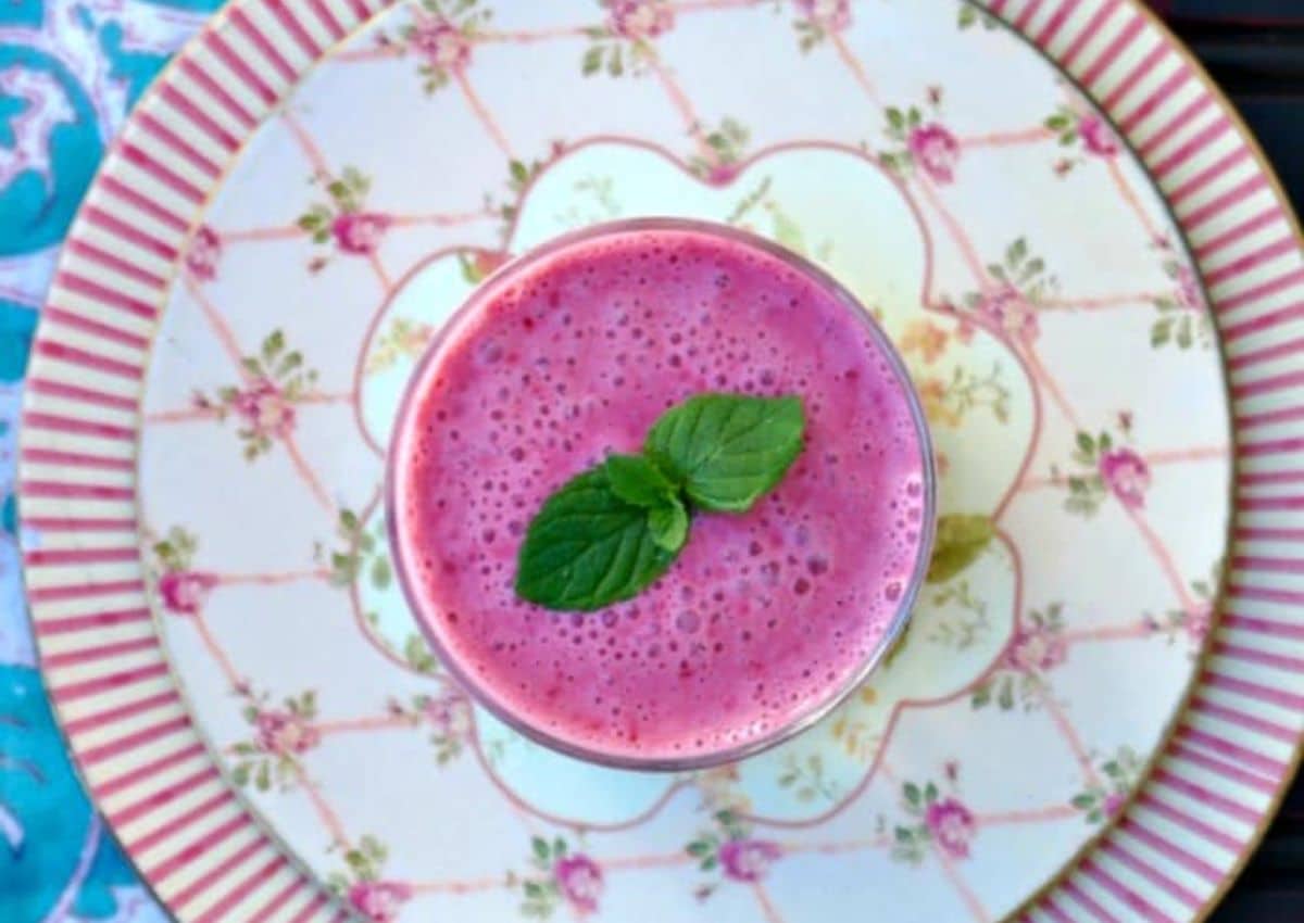 Cranberry raspberry smoothie in a clear glass topped with mint.