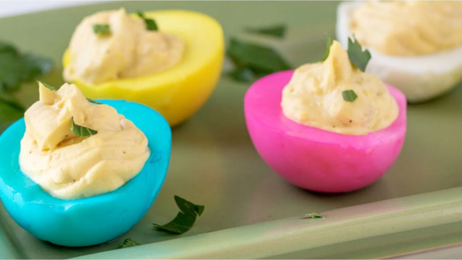 Pastel deviled eggs on a wooden cutting board.