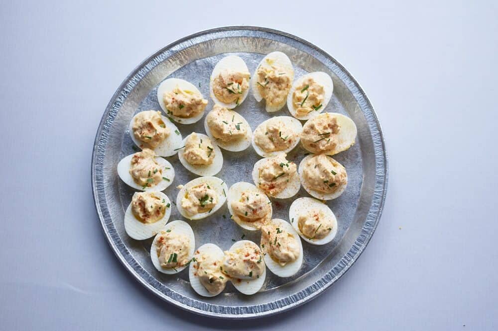 Deviled eggs on a metal serving tray.