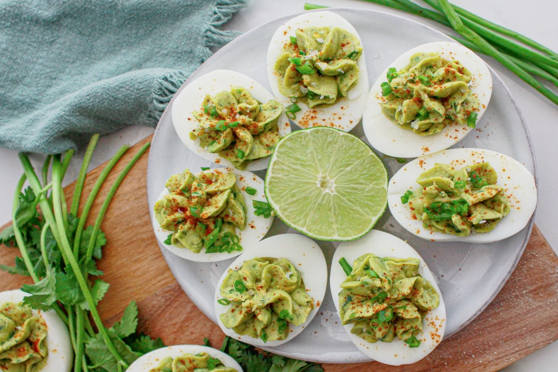 Deviled eggs filled with guacamole with a lime in the cetner.