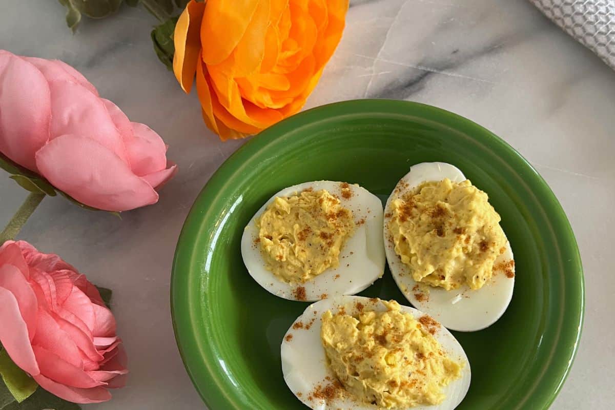 Three deviled eggs on a green plate.