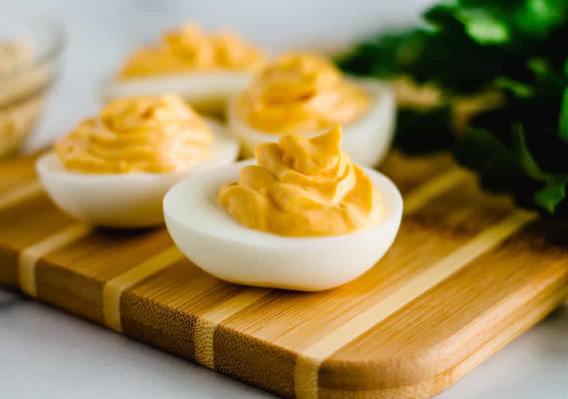 Hummus deviled egg on a wooden cutting board.