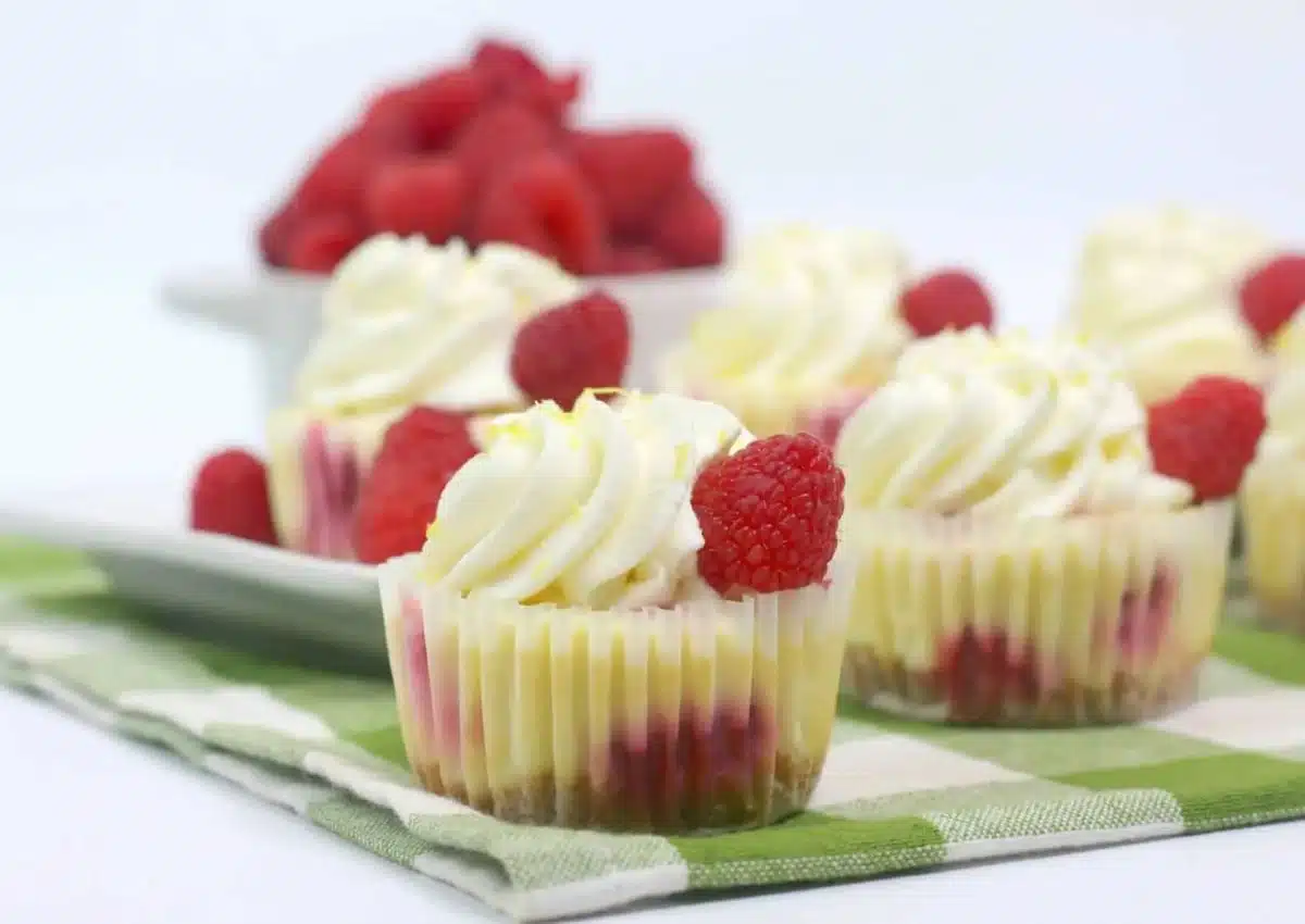 Mini lemon raspberry cheesecakes on a green and white napkin.