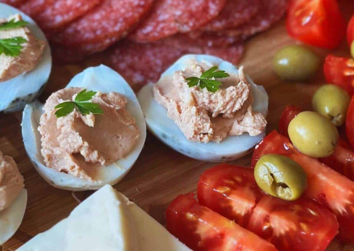 Pate deviled eggs on a cutting board surronded by vegetables.