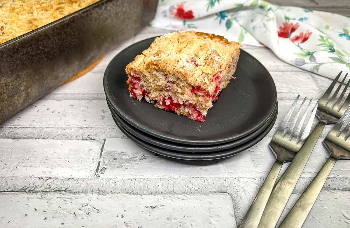 Slice of raspberry crumb cake on a black plate.