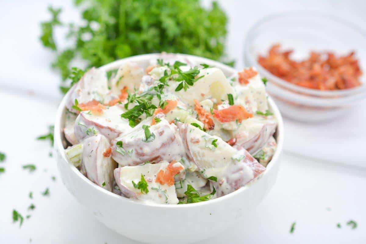 White bowl full of red skin potato salad.