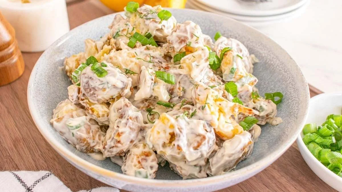 Smashed potato salad in a white bowl.
