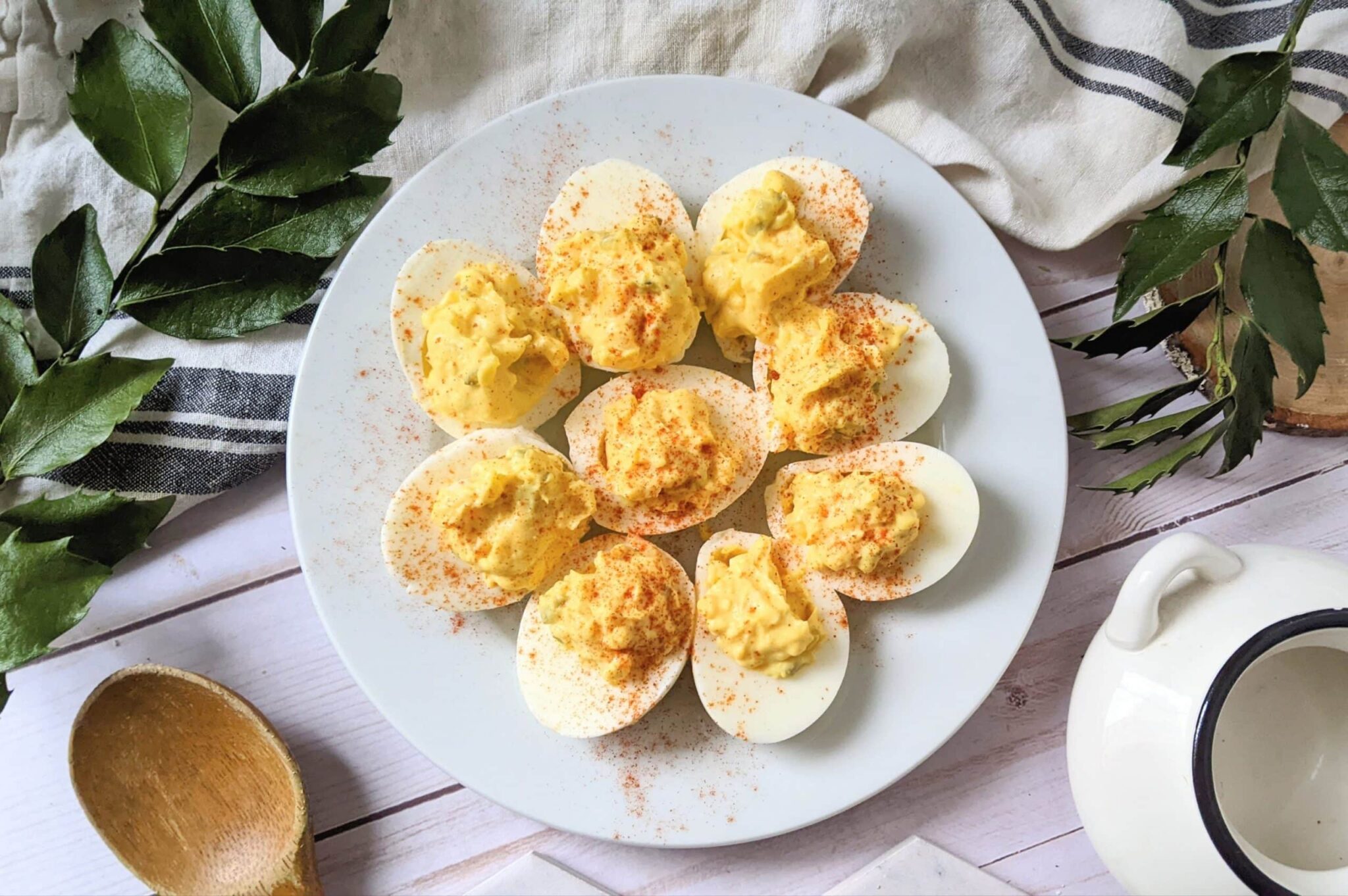 Deviled eggs topped with paprika on a white plate.