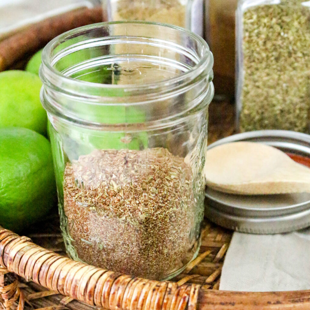A clear mason jar half filled with carne asada seasoning spices.
