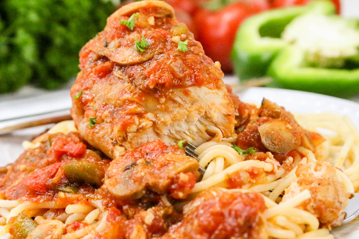 Cooked chicken thighs with sliced mushrooms in a red sauce.