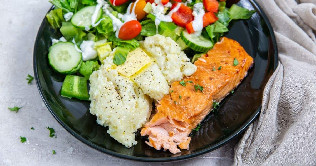Salmon, mashed cauliflower, and salad on a plate.