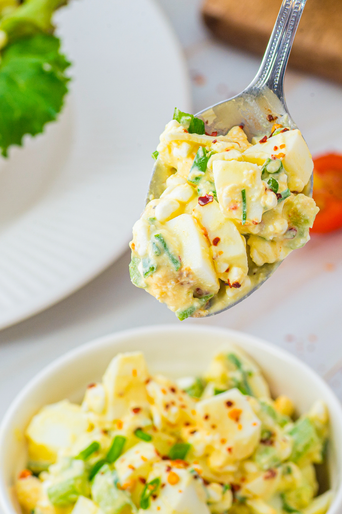 A silver spoon full of egg salad.