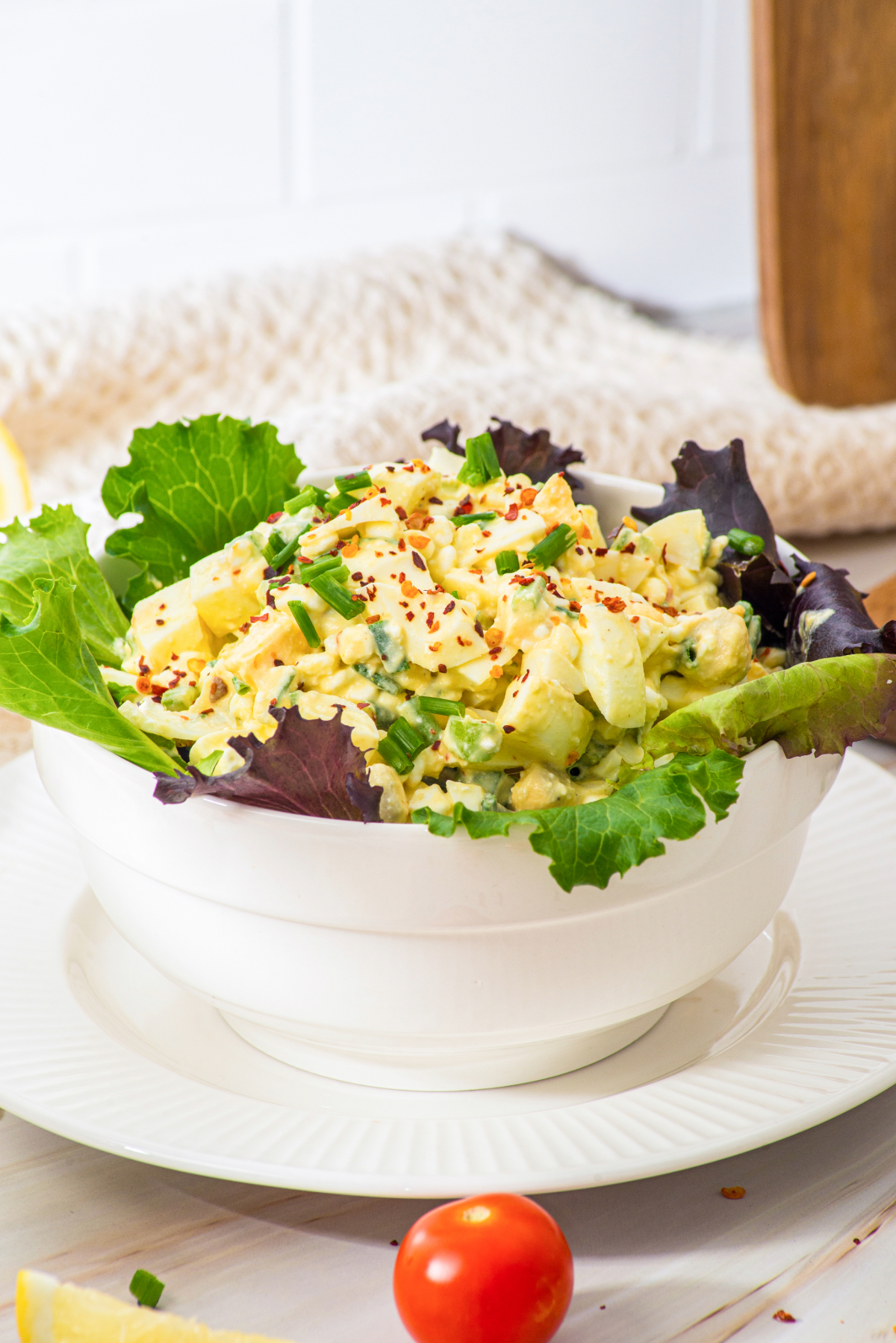 Egg salad made with cottage cheese instead of mayonnaise in a white serving bowl layered with lettuce leaves.