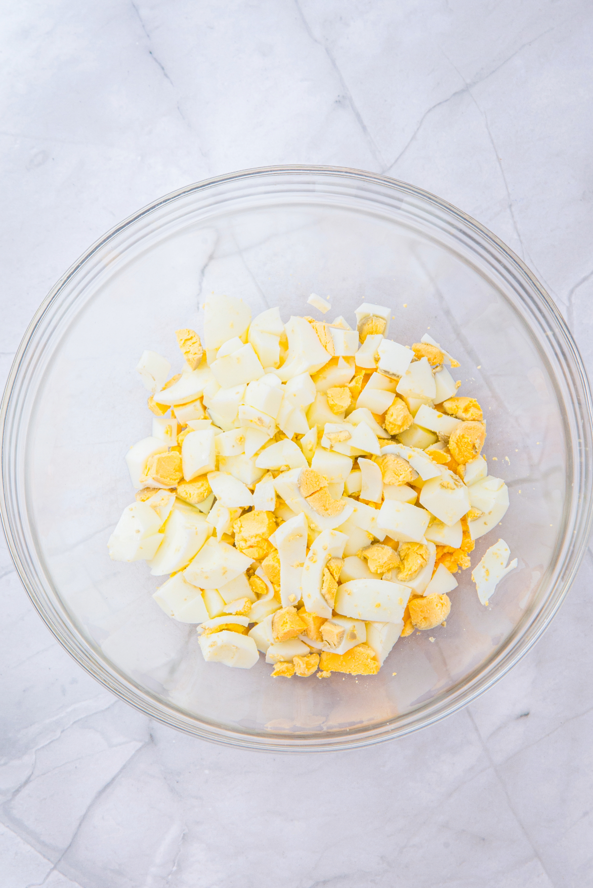 Diced hard boiled eggs in a clear mixing bowl.