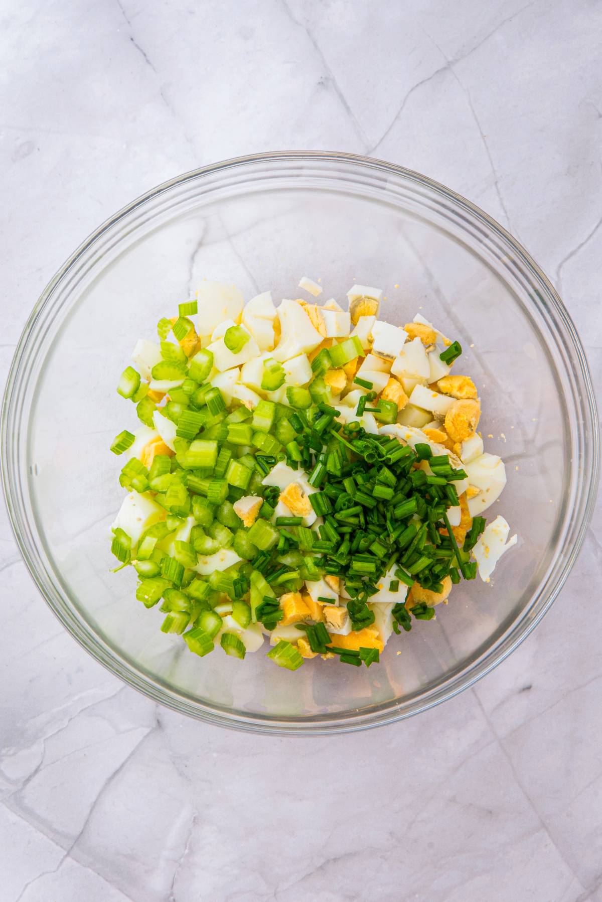 Ingredients to make hard boiled eggs in a clear mixing bowl.