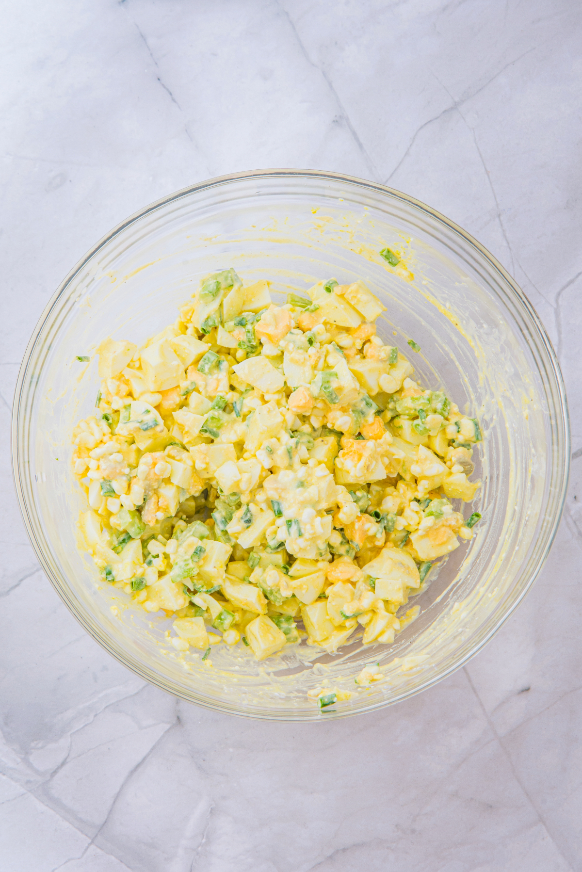 Egg salad mixed with cottage cheese in a mixing bowl.