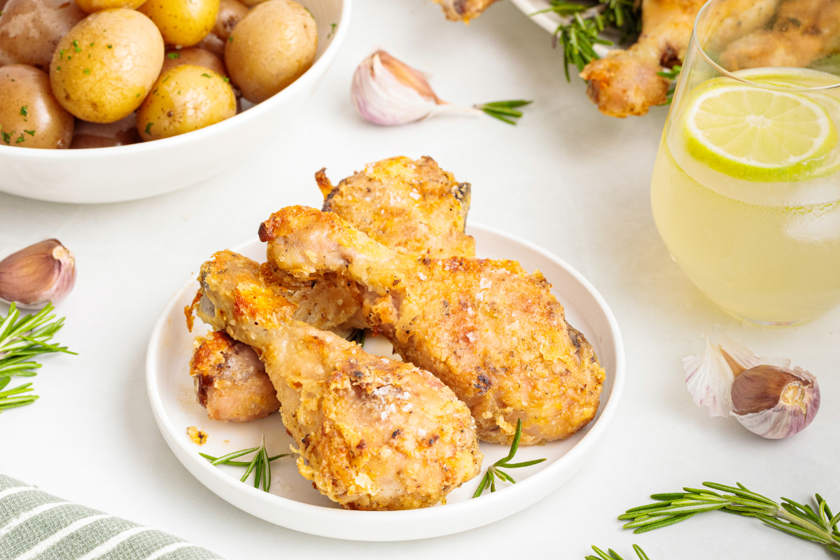 Oven baked chicken on a white plate with a lemonade beverage on the side.