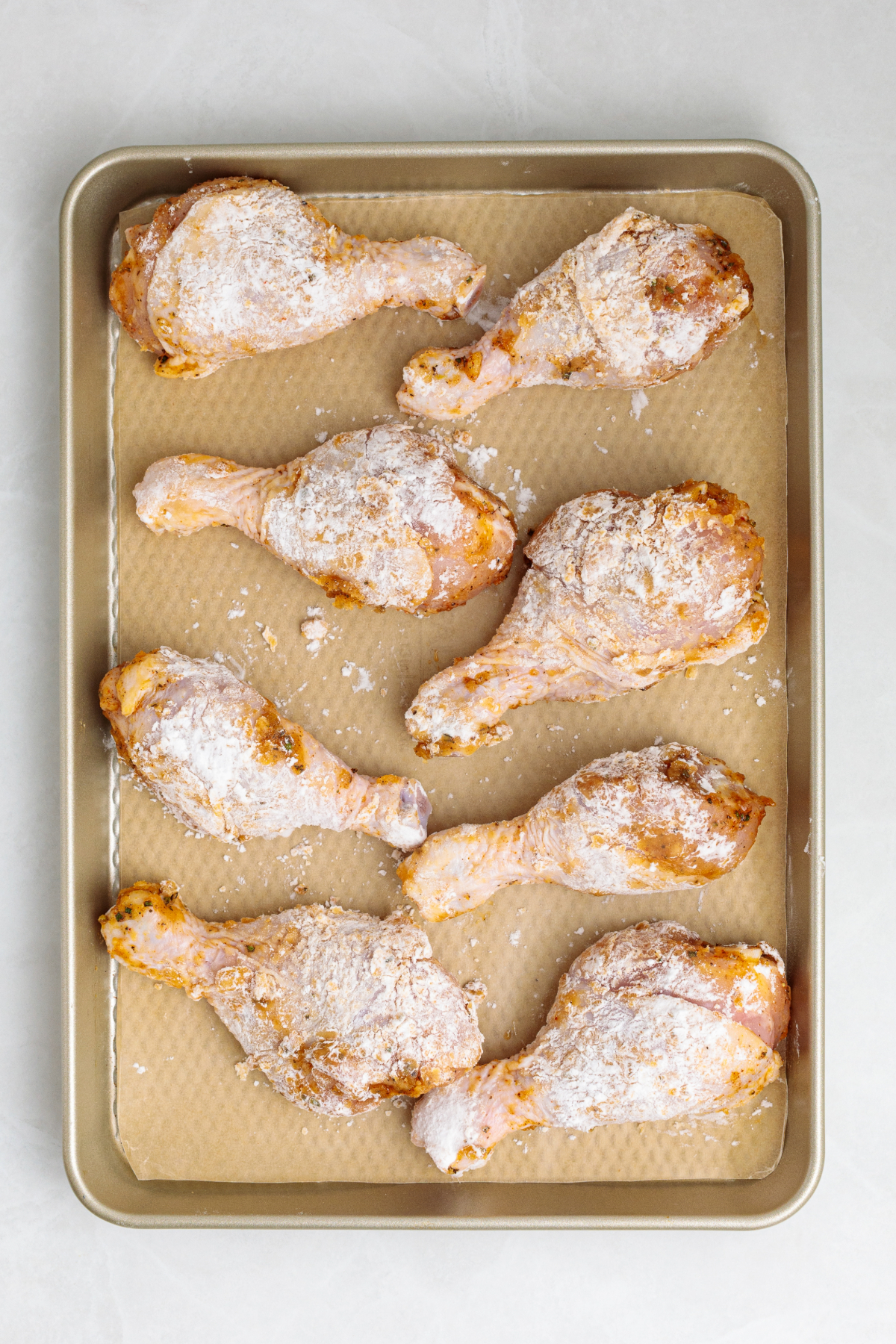 Chicken pieces on a baking sheet before putting in the oven.
