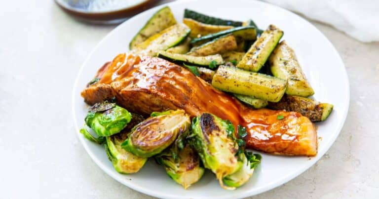 Salmon, brussel sprouts, and zucchini on a plate.
