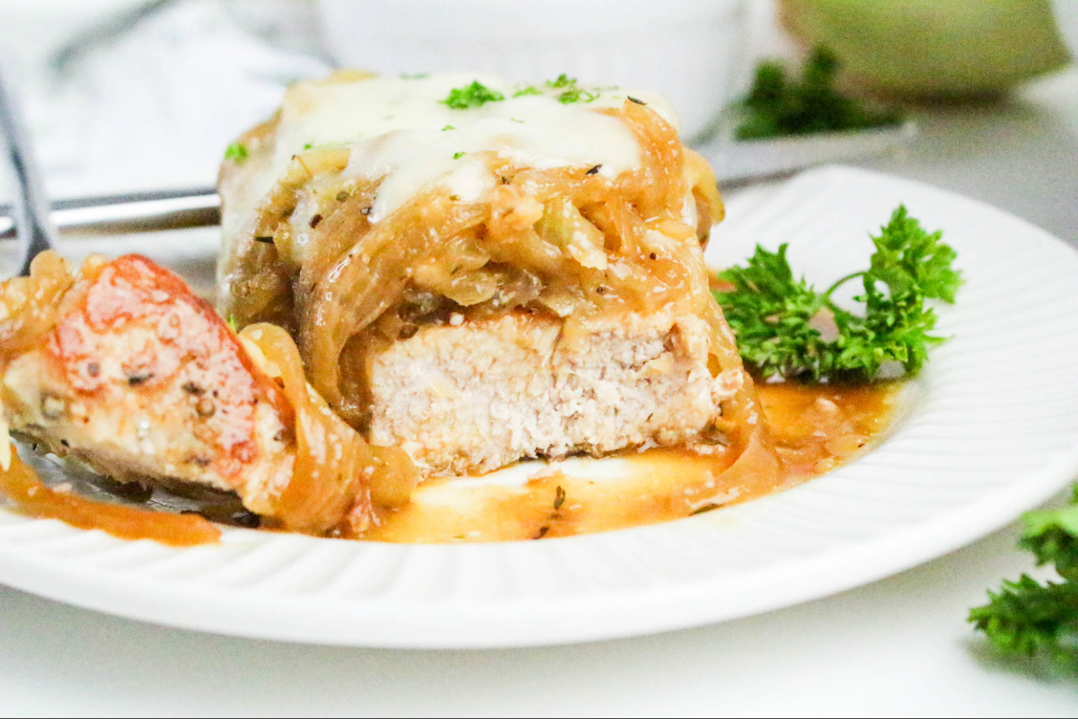 Dinner plate with pork chop topped with sautéed onions.