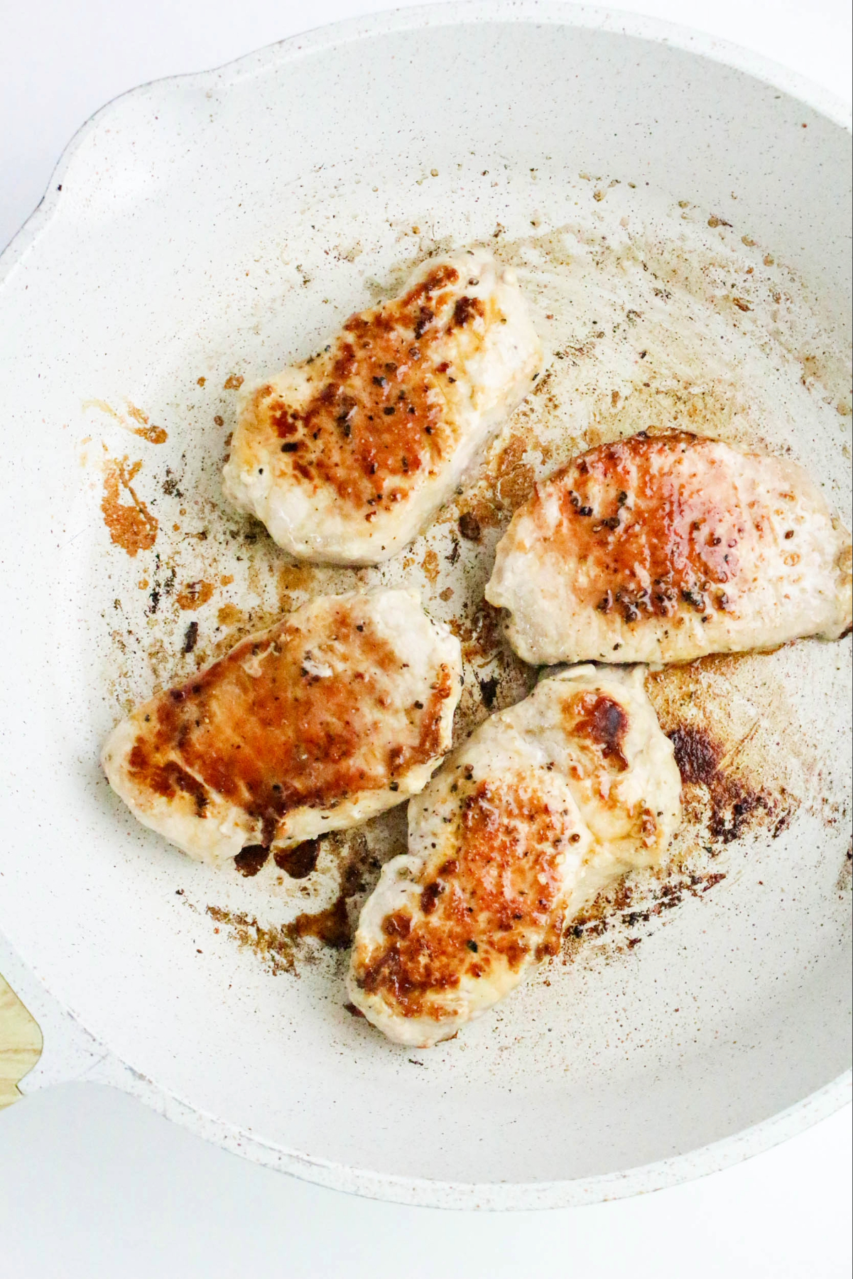 Searing pork chops in a skillet.