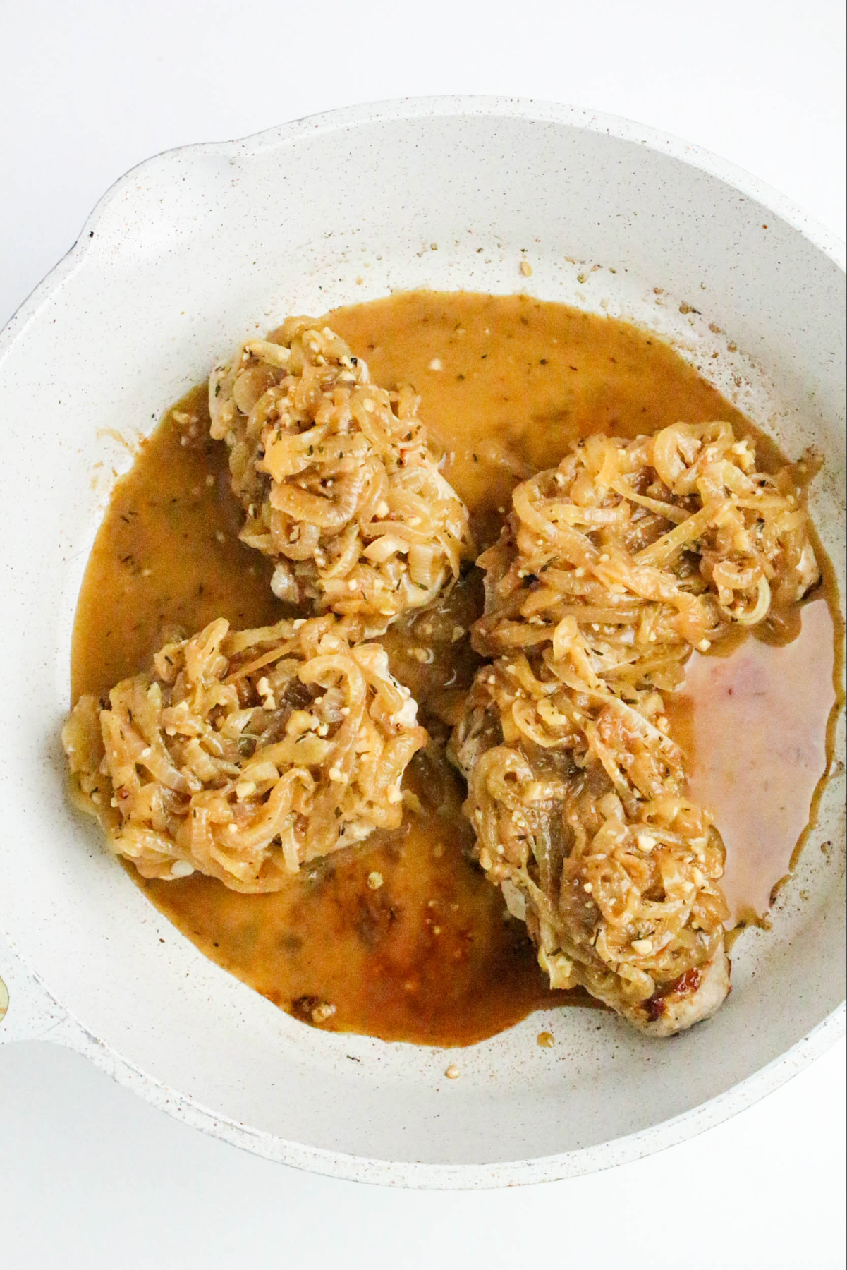 Topping pork chops with French onions and beef broth sauce.
