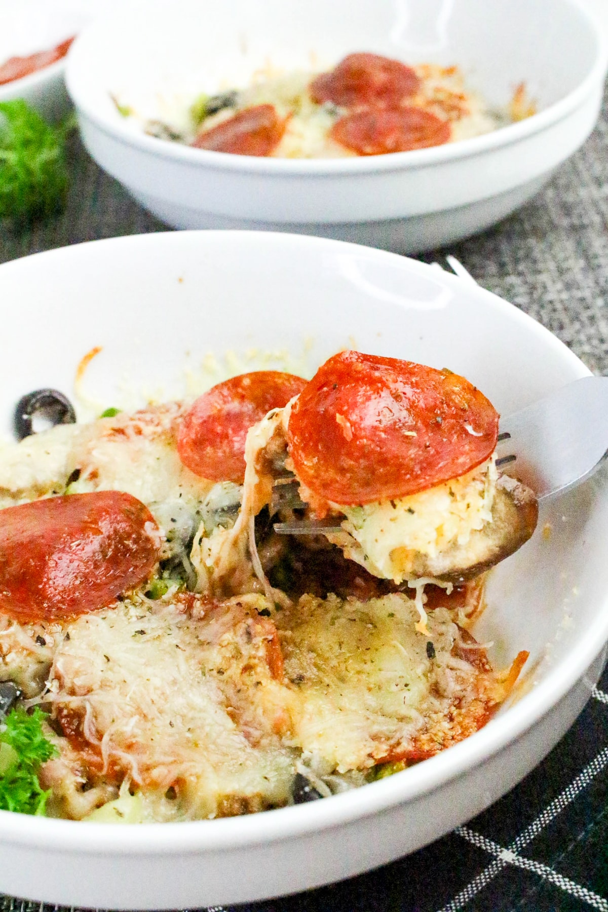 Pizza toppings with sauce in a white bowl with melted cheese.