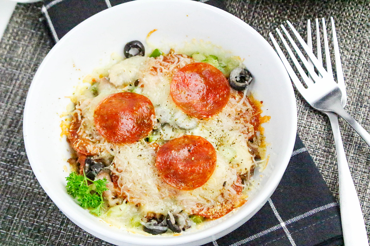 Oven baked pizza without the crust in a white bowl topped with pepperoni slices.