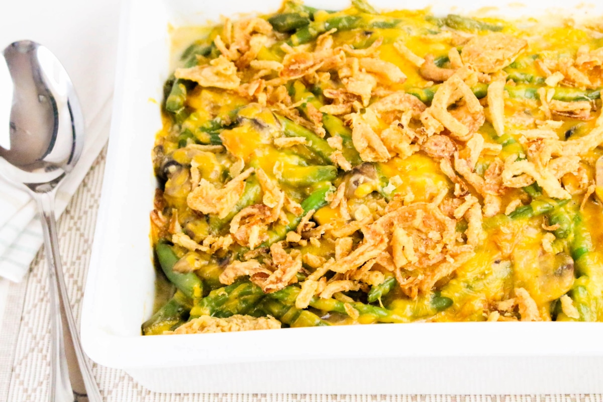 Casserole topped with fried onions and cheese with a silver serving spoon on the side.