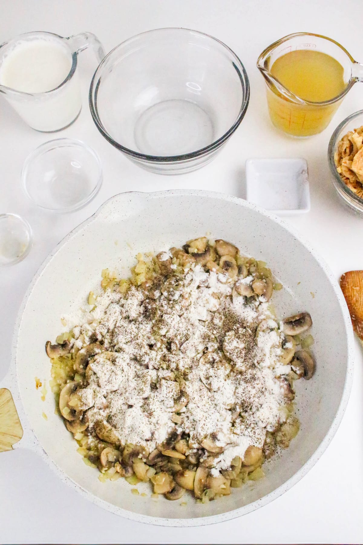Sautéed onions and mushrooms in a white skilled topped with flour.