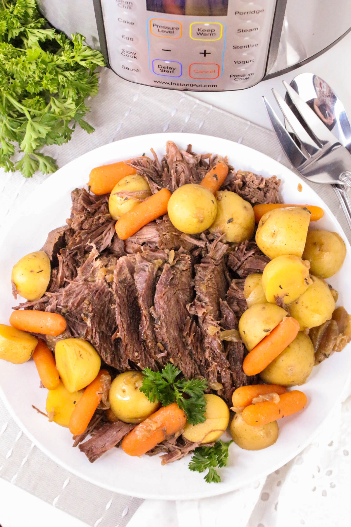 Overhead view of cooked beef and vegetables on a white serving plate.