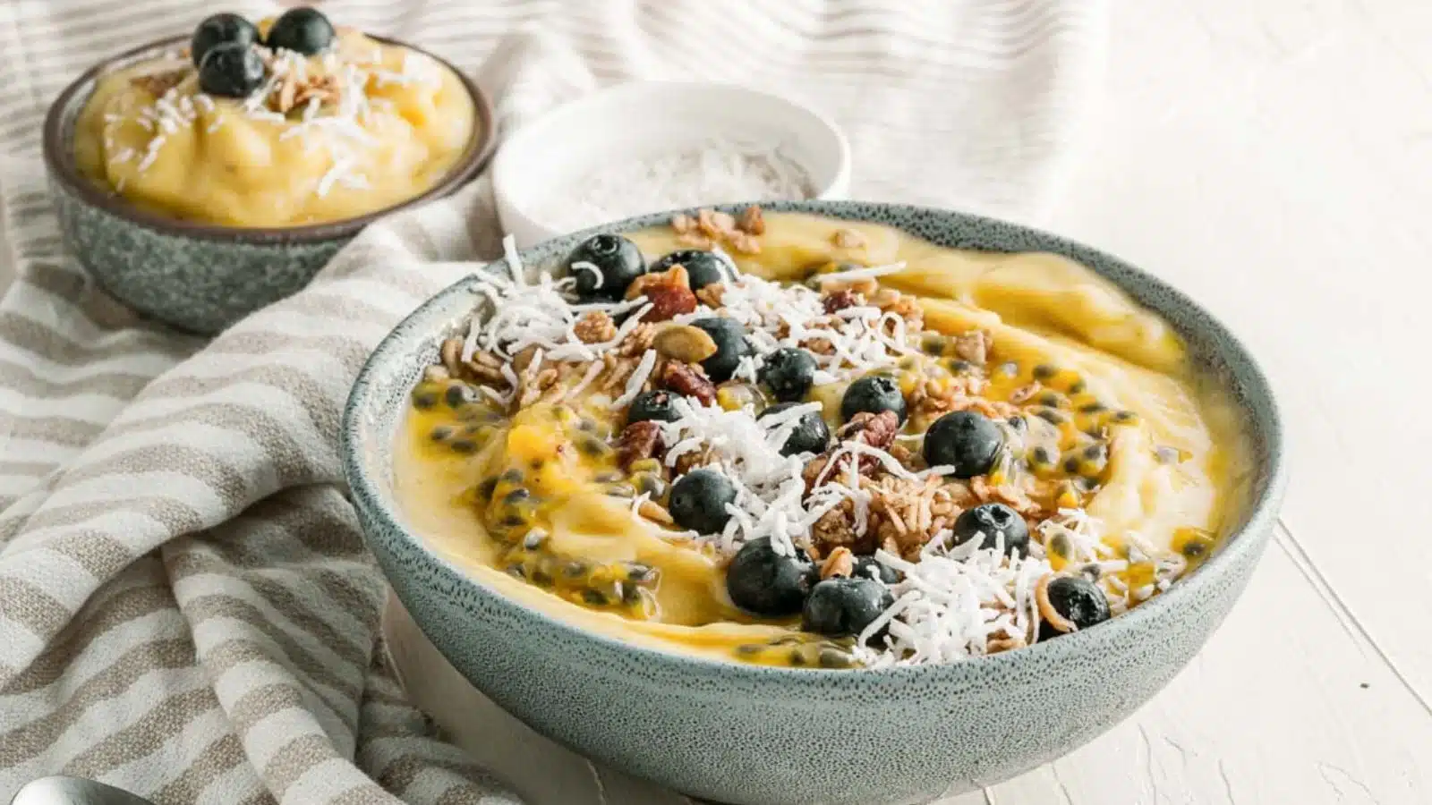 Bowl full of mango smoothie and topped with shredded coconut.