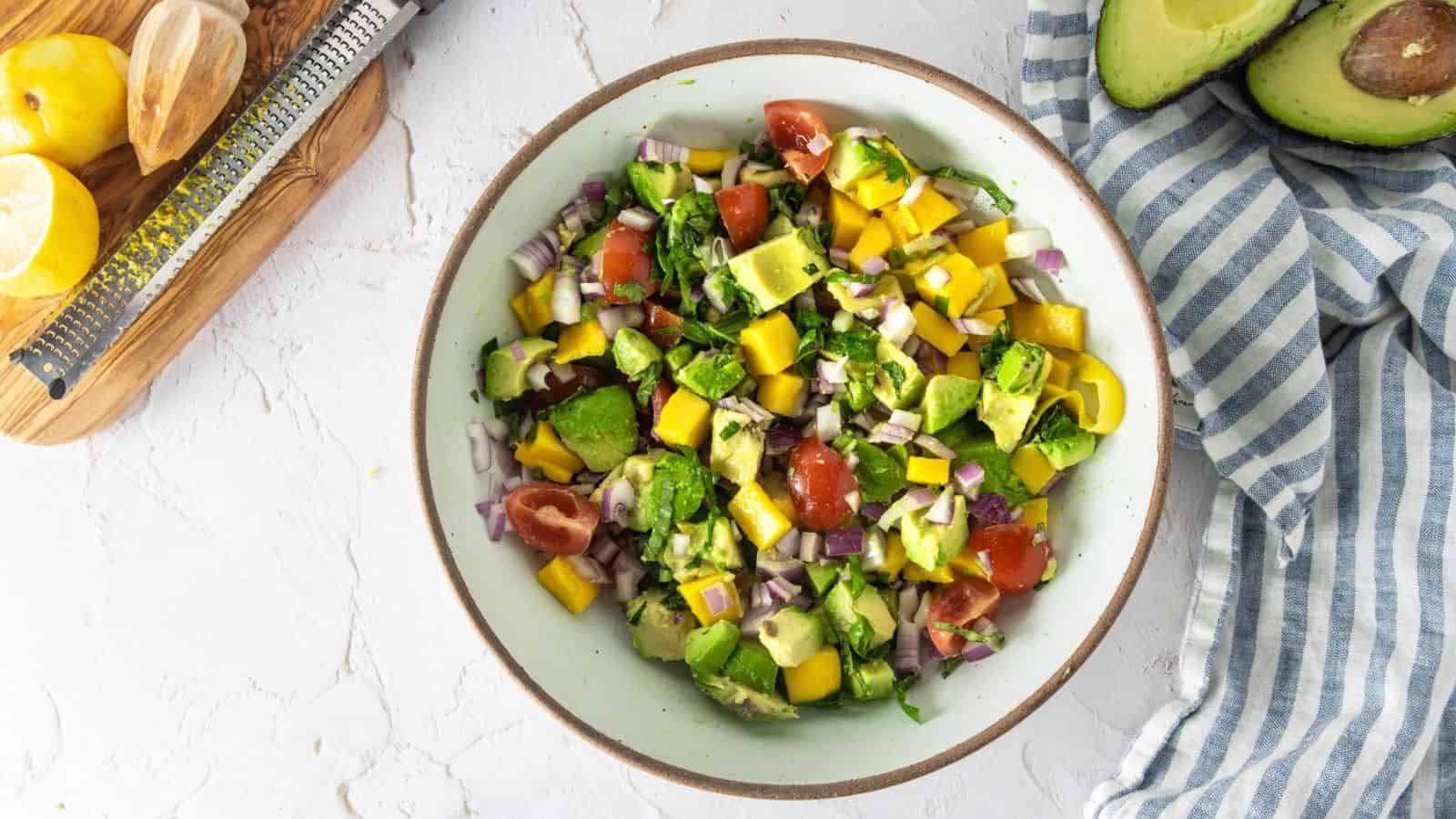 Bowl full of mango avocado salad on a counter.